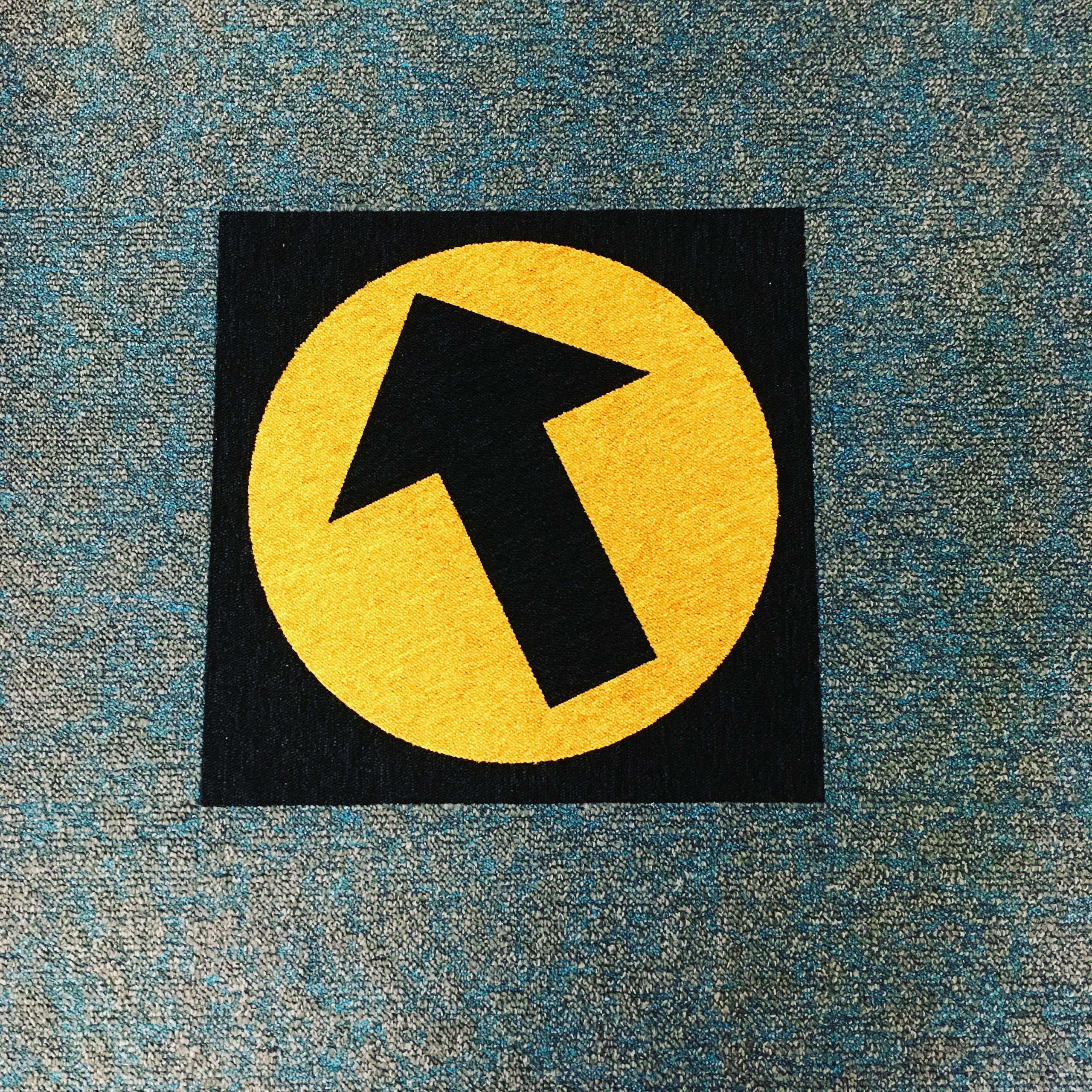 Wayfinding carpet tile replacement with black & yellow arrow